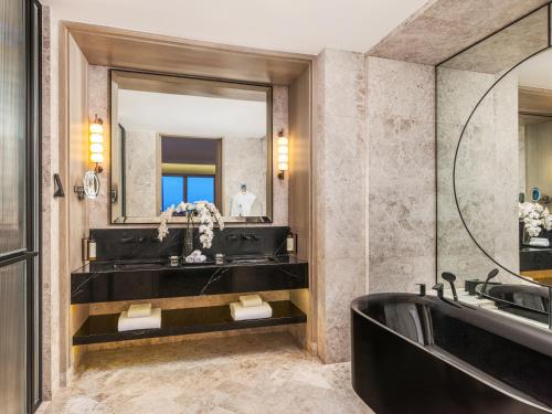 a bathroom with a tub and a sink and a mirror at Fairmont Singapore in Singapore