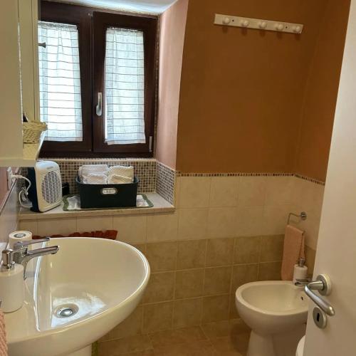 a bathroom with a sink and a toilet and a window at La casetta in Serracapriola