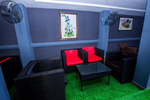a living room with two chairs and a red chair at Doreen Grand Hotel and suites in Lagos