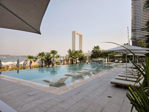 a large swimming pool with white chairs and palm trees at Beach Please in Dubai