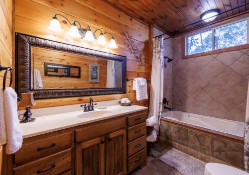 une salle de bain avec un lavabo, une baignoire et un miroir dans l'établissement Paradise Found - Lookout Mt Edge, Hot Tub & Views, à Mentone