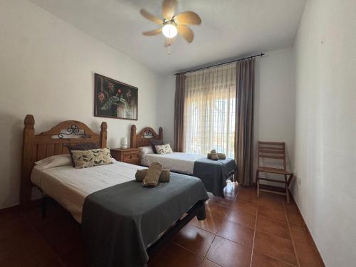 フリヒリアナにあるTwo Bedroom one bathroom with communal swimming poolのベッド2台と天井ファン付きの寝室