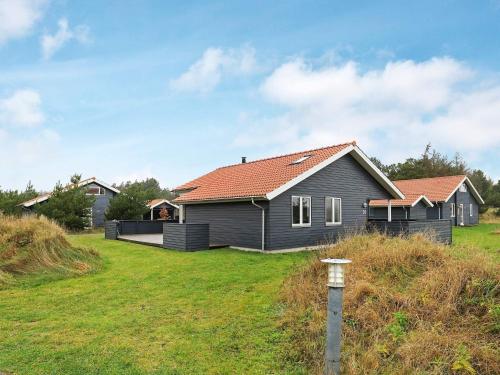 a gray house with a red roof on a yard at Luxury Spa Retreat by Sea - By Traum Ferienwohnungen in Ulfborg