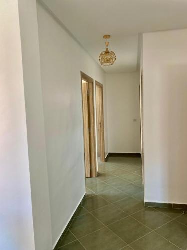 an empty hallway with white walls and a chandelier at Belle Appartement familiale,couple marié in Marrakech