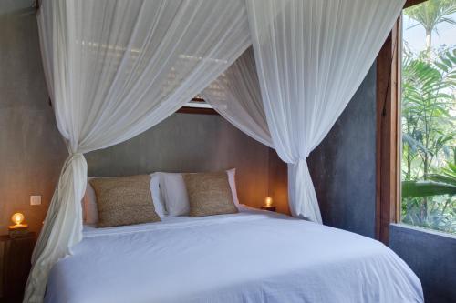a bedroom with a white bed with a window at ZIN Berawa Villas & Bungalows in Canggu