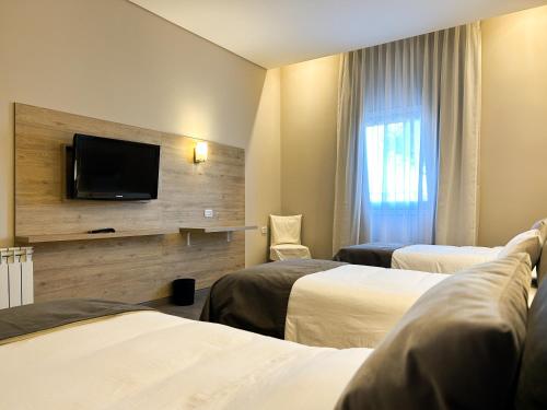 a hotel room with two beds and a flat screen tv at Hotel Finca Alvear in General Alvear