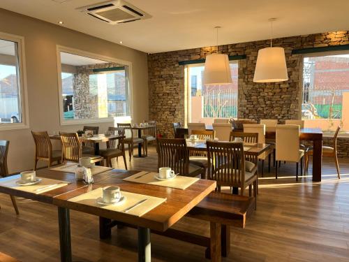 a restaurant with wooden tables and chairs and windows at Hotel Finca Alvear in General Alvear