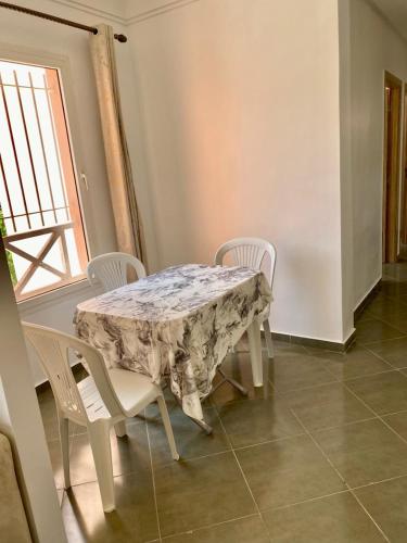 a table and chairs in a room with a window at Belle Appartement familiale,couple marié in Marrakech