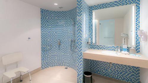 a blue tiled bathroom with a sink and a shower at Holiday Inn Express Baruna by IHG in Kuta