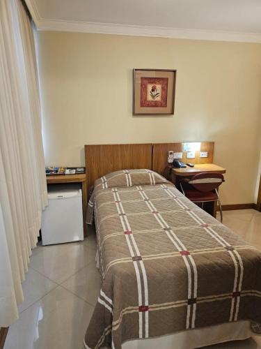 a hotel room with a bed and a desk and a desk at Barbur Center Hotel in Ponta Grossa