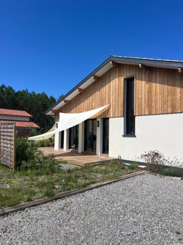 a house with a wooden roof and a porch at Maison entre océan et forêt landaise in Vielle-Saint-Girons