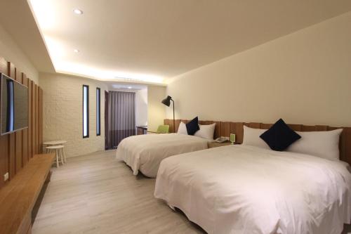 a hotel room with two beds and a television at Muguang Inn in Hengchun