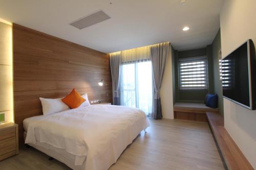 ein Schlafzimmer mit einem weißen Bett und einem großen Fenster in der Unterkunft Muguang Inn in Altstadt von Hengchun