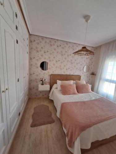 a bedroom with a large bed with pink pillows at Alboran - RETAMAR EXPERIENCE in Almería