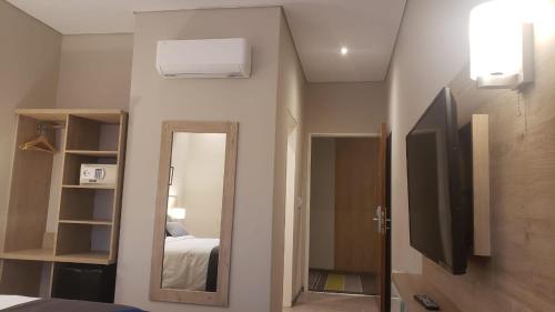 a bedroom with a mirror and a bed and a tv at Hotel Finca Alvear in General Alvear