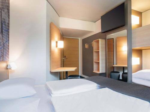 a hotel room with two beds and a tv at B&B HOTEL Wismar in Wismar