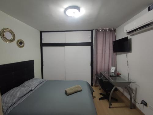 a bedroom with a bed and a desk and a window at Habitación en apartamento compartido frente a Maiquetía! in Maiquetía
