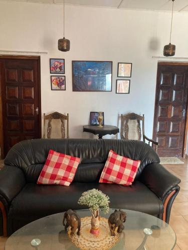 a living room with a black leather couch and a glass table at Ameeila villa in Kandy