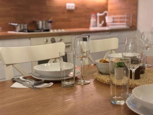 a wooden table with wine glasses and plates on it at Mileticova street, keyless, AC in Nivy