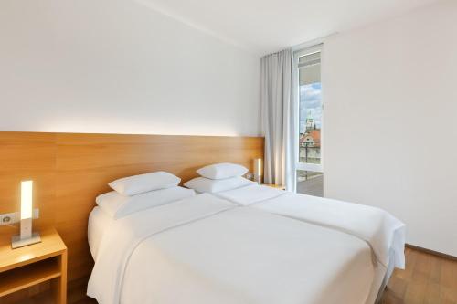 a white bed in a room with a window at Austria Trend Hotel Congress Innsbruck in Innsbruck