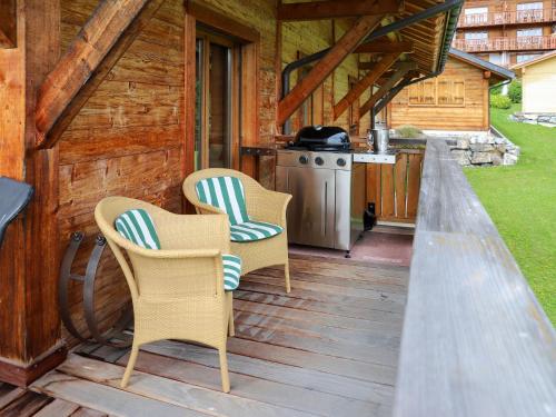 a porch of a cabin with two chairs and a stove at Chalet Khamariah by Interhome in Villars-sur-Ollon