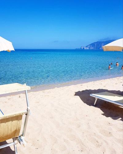 a beach with a table and chairs and the ocean at Casa Vacanza il Mandorlo in Domusnovas