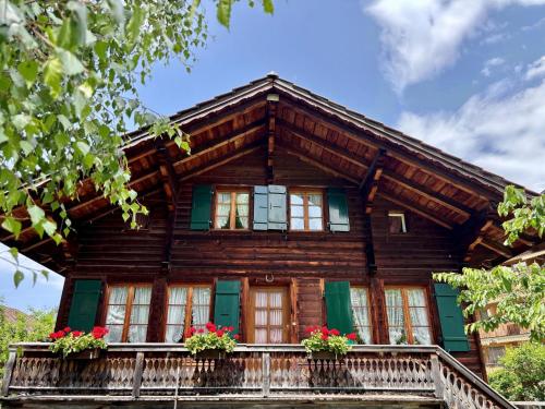 una casa de madera con flores en el balcón en Apartment Lena- Chalet by Interhome, en Gstaad