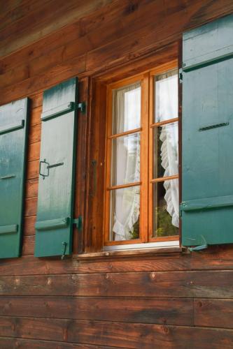 Una ventana en una casa de madera con contraventanas verdes. en Apartment Lena- Chalet by Interhome, en Gstaad