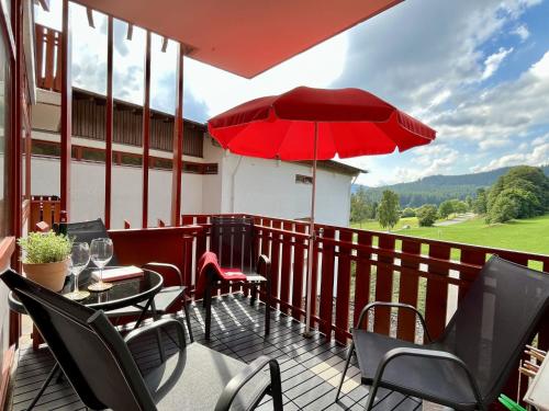 a patio with a table and chairs and a red umbrella at Apartment App- 1406 - EX-Kurhotel Schluchsee by Interhome in Schluchsee