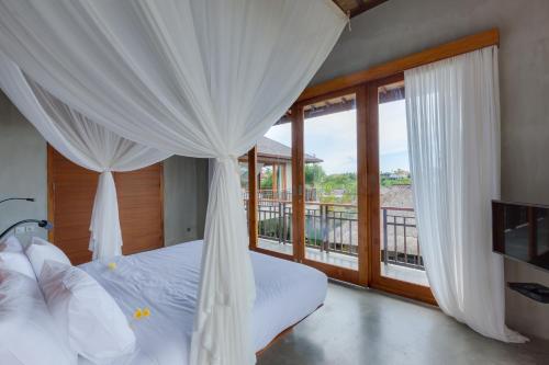 a bedroom with a bed with curtains and a balcony at ZIN Berawa Villas & Bungalows in Canggu