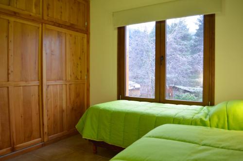 a room with two beds and a large window at La Araucaria in Villa La Angostura