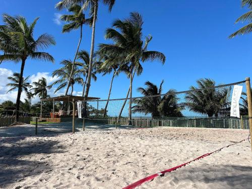 a volley ball court on a beach with palm trees at Bangalô moderno e super bem equipado in Passo de Camarajibe