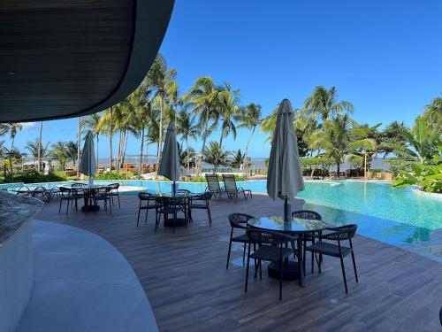 a patio with tables and chairs next to a swimming pool at Bangalô moderno e super bem equipado in Passo de Camarajibe