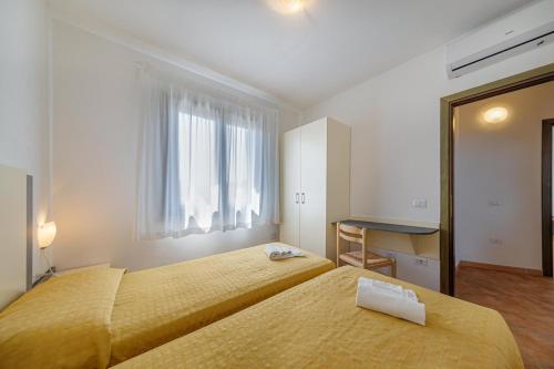 a hotel room with two beds and a window at Residenza Le Farfalle in Tergu