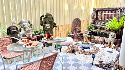 a room with statues and tables with food on them at Baan inta hostel - บ้านอินตาโฮสเทล in Phra Nakhon Si Ayutthaya