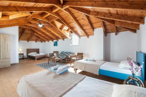 a bedroom with two beds and a living room with wooden ceilings at Blue Pearl Apolakkia in Apolakkiá