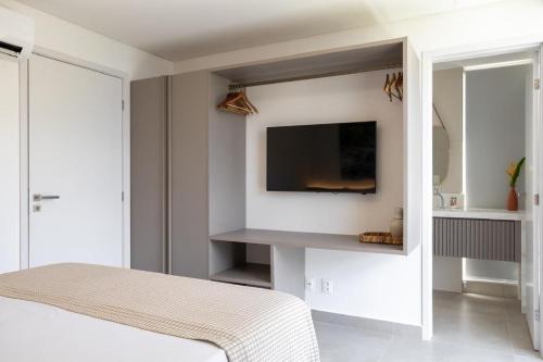 a bedroom with a tv on a white wall at Bangalô moderno e super bem equipado in Passo de Camarajibe