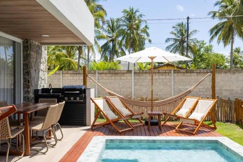 a patio with a hammock and a table and chairs at Bangalô moderno e super bem equipado in Passo de Camarajibe