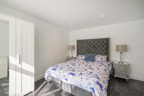 a bedroom with a bed with a blue and white comforter at Modern Flat near Wembley stadium in The Hyde