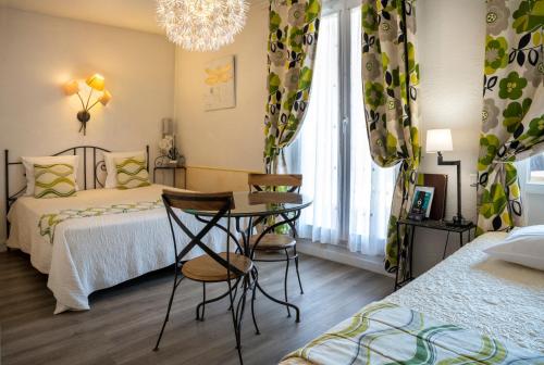 a bedroom with two beds and a table and chairs at Hotel Toppin in Cavaillon