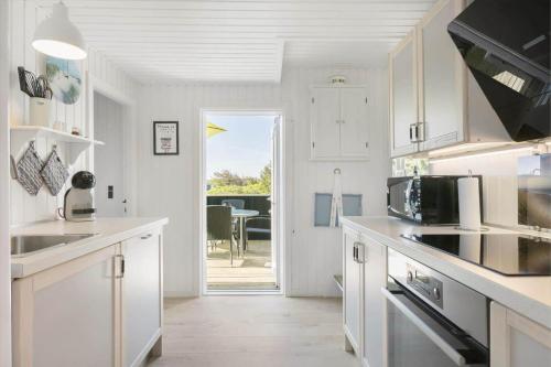a kitchen with white cabinets and a door leading to a patio at BL1729-Blokhus-Jens-Baerentsvej-36 in Blokhus