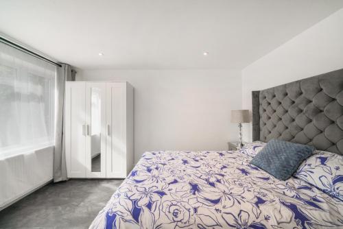 a bedroom with a bed with a blue and white comforter at Modern Flat near Wembley stadium in The Hyde