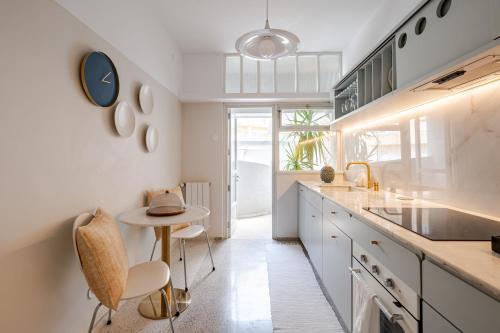 a kitchen with white cabinets and a table and chairs at UNIQUE Modernist Duplex apartment & PARKING in Porto