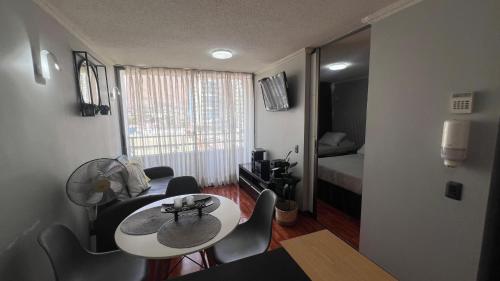 a small room with a table and chairs and a bedroom at Departamentos Alpro Cavancha in Iquique