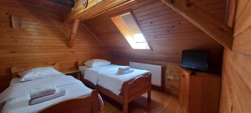 a attic room with two beds and a television at Camere de Inchiriat Ceahlau in Ceahlău
