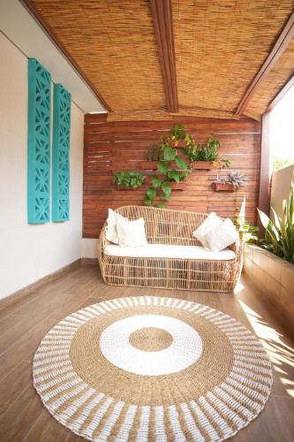 a room with a rattan couch and a large rug at Pousada Aconchego Noronha in Fernando de Noronha