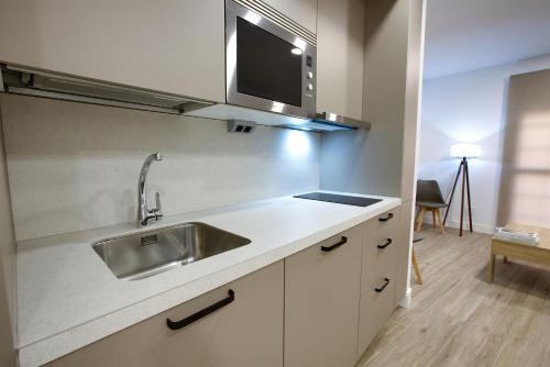 Una cocina con un fregadero y un televisor en la pared. en Cuencaloft Hurtado de Mendoza, en Cuenca