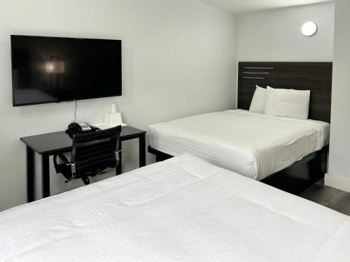 a hotel room with two beds and a desk and a tv at Motel 6 Santa Cruz, CA in San Jose
