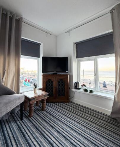 a living room with a flat screen tv and two windows at Sids restaurant and bar with rooms in Cardiff