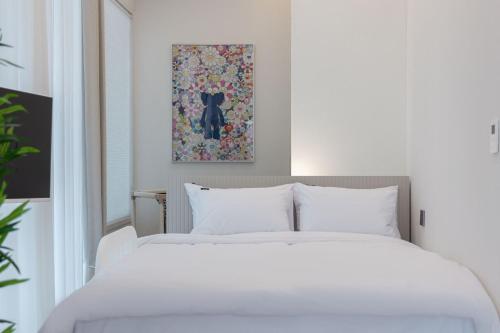 a bedroom with a white bed and a painting of a black cat at 해운대 웨이브 Haeundae wave in Busan